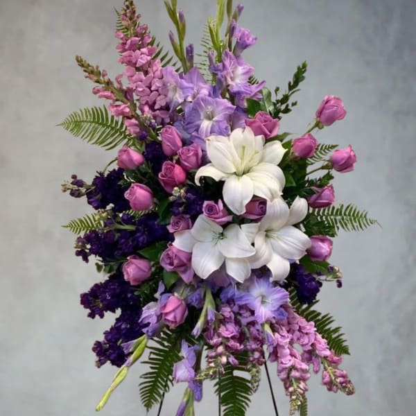 Standing floral spray with white lilies, pink roses, and purple blooms