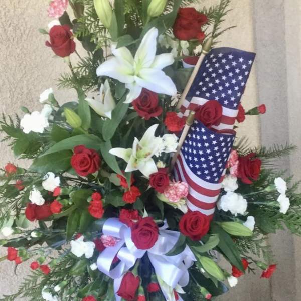 Standing floral spray with red roses, white lilies, and American flags