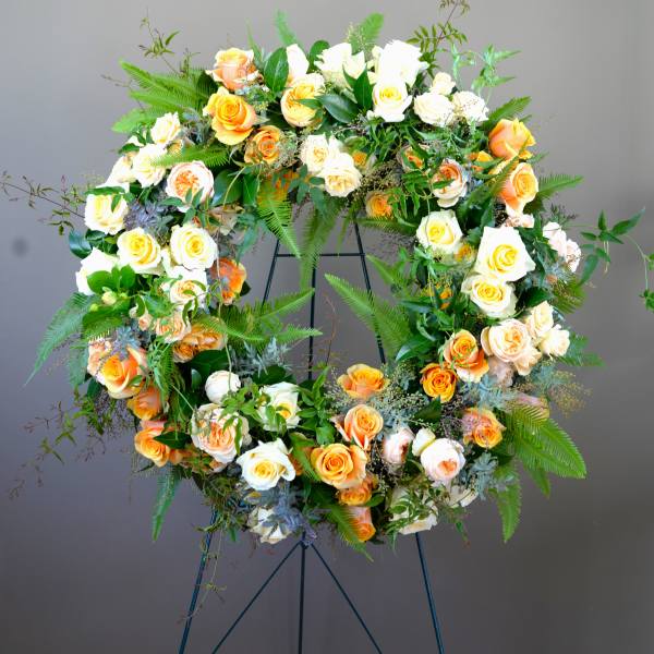 Large floral wreath of peach and white roses on a stand