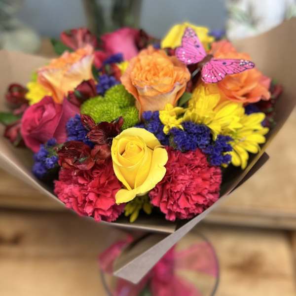 Bright mixed bouquet of roses, carnations, and daisies with butterfly picks