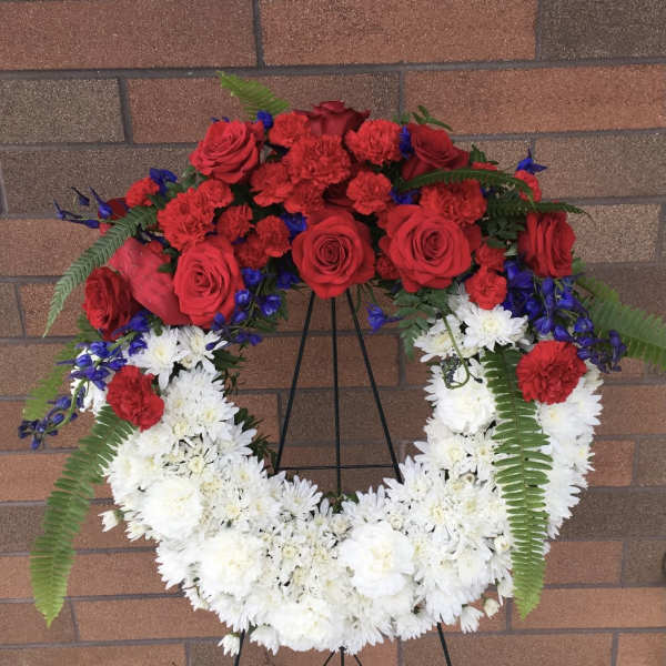Red and white floral wreath on a black stand