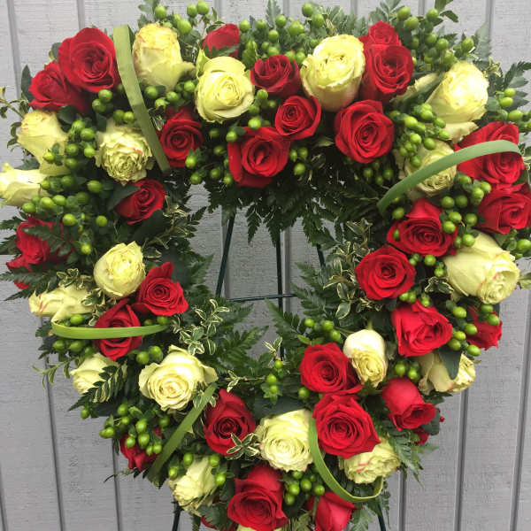 Heart-shaped wreath of red and cream roses on a stand