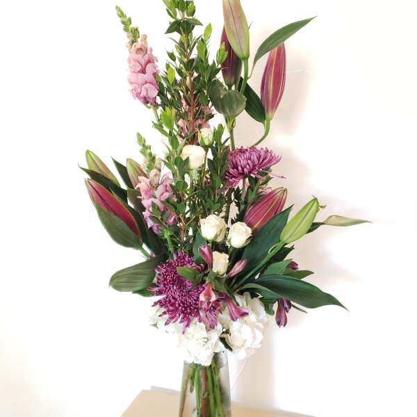 Tall bouquet of lilies, chrysanthemums, and white roses in a glass vase