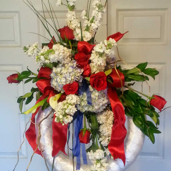 Large floral wreath with red roses and white blooms on a stand