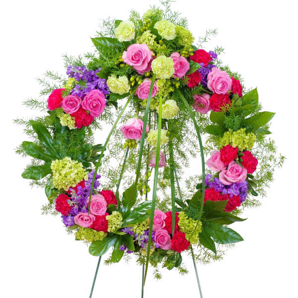 Bright standing wreath of pink roses, red carnations and green blooms on a metal easel
