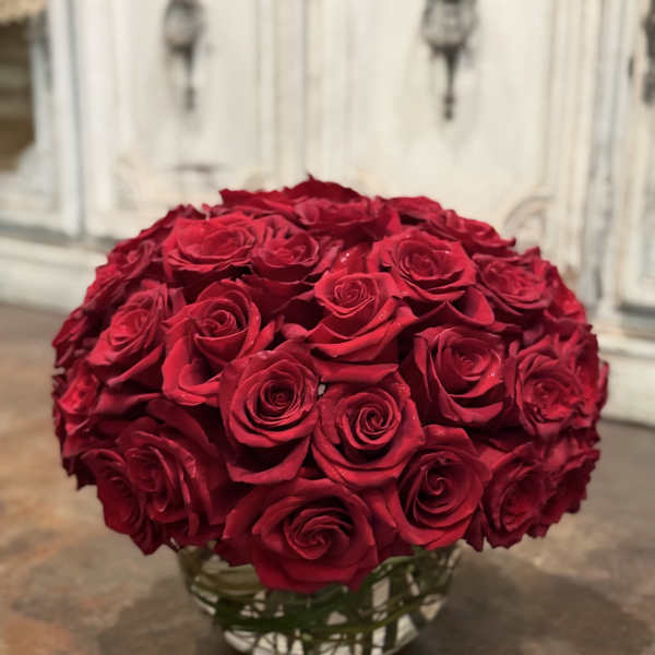 Round bouquet of red roses in a clear glass vase