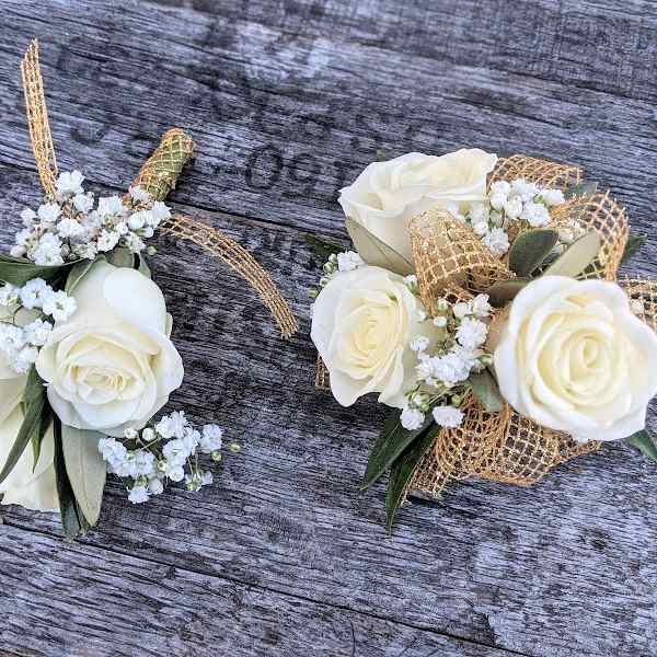 Two white rose corsages with baby's breath and gold ribbon accents