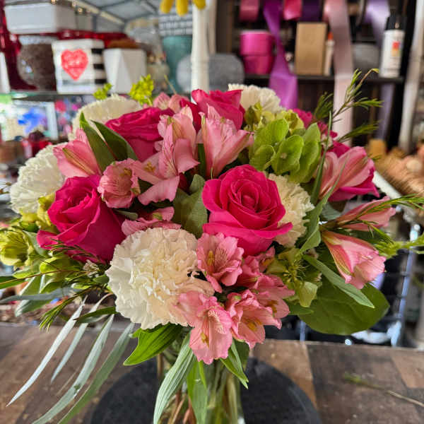 Pink roses and alstroemeria in a glass vase with white carnations