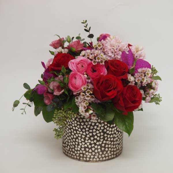 Red and pink roses arranged in a patterned vase