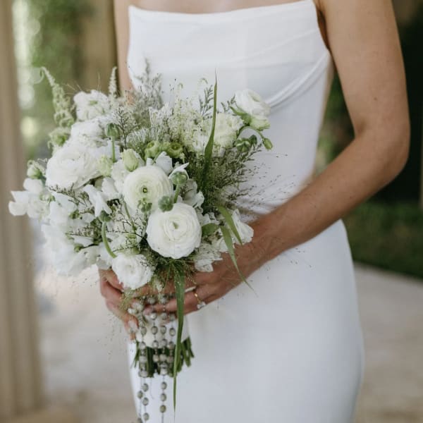 Bride holding a white bouquet with trailing bead strands