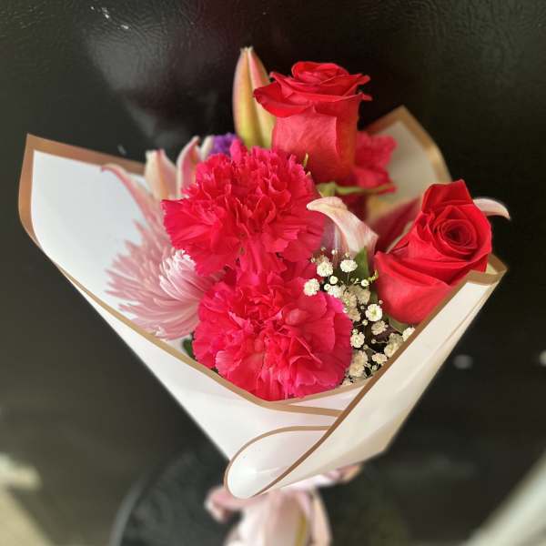 Bouquet of red roses and pink carnations wrapped in white paper