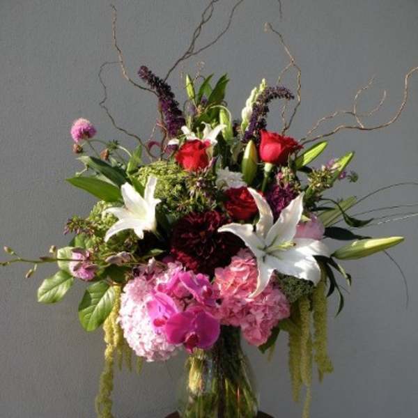 Tall mixed bouquet in a glass vase with white lilies, pink roses, and hydrangeas