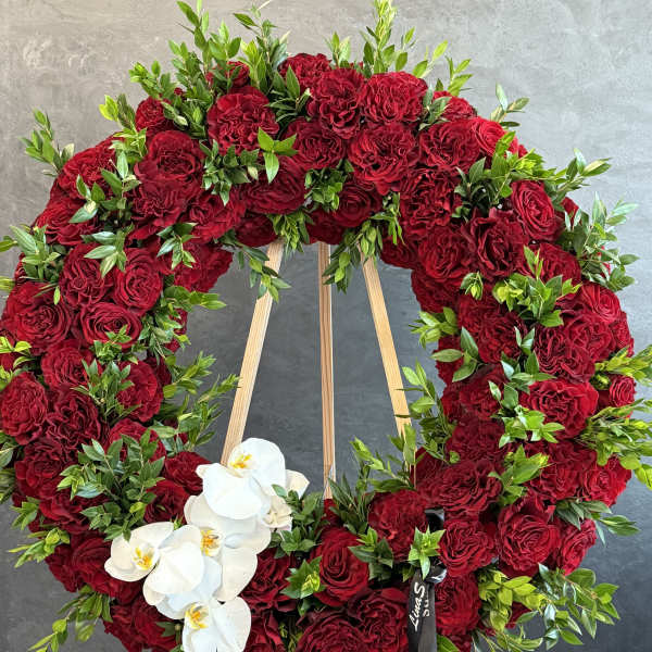 Heart-shaped wreath of red roses with white orchids on a wooden easel