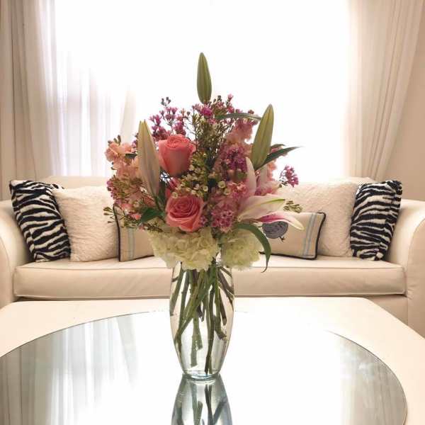 Pink roses and lilies arranged in a clear glass vase
