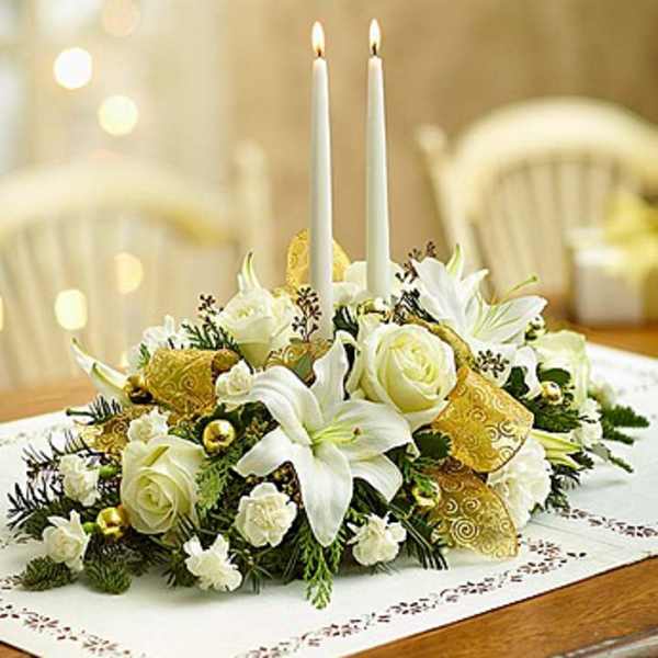 White floral centerpiece with two lit taper candles
