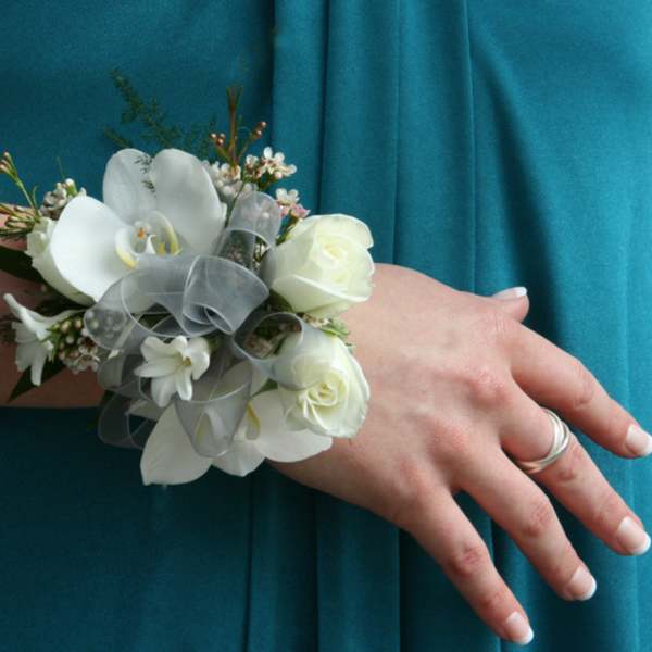 White floral wrist corsage with ribbon on a person's wrist