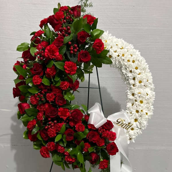 Heart-shaped floral wreath with red and white flowers on a stand
