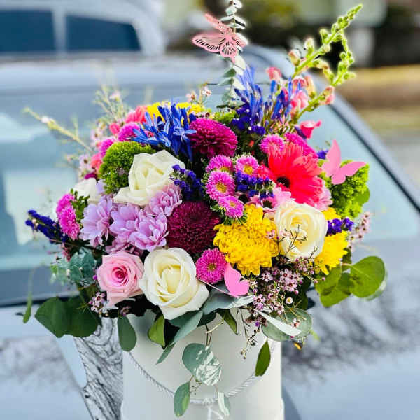 Colorful mixed bouquet in a white hatbox on a car hood