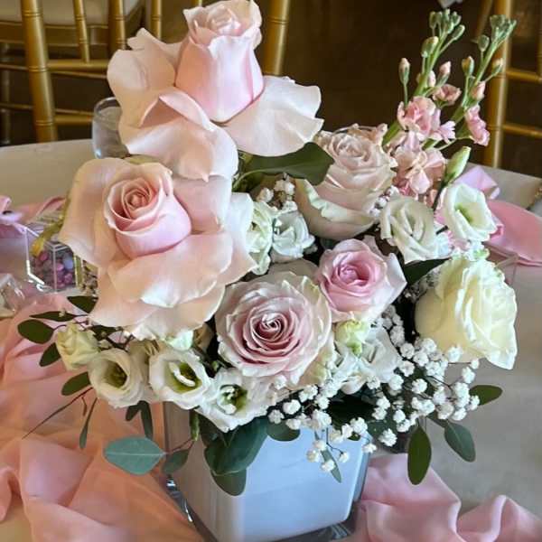 Pink and white rose centerpiece in a square vase with pink draping