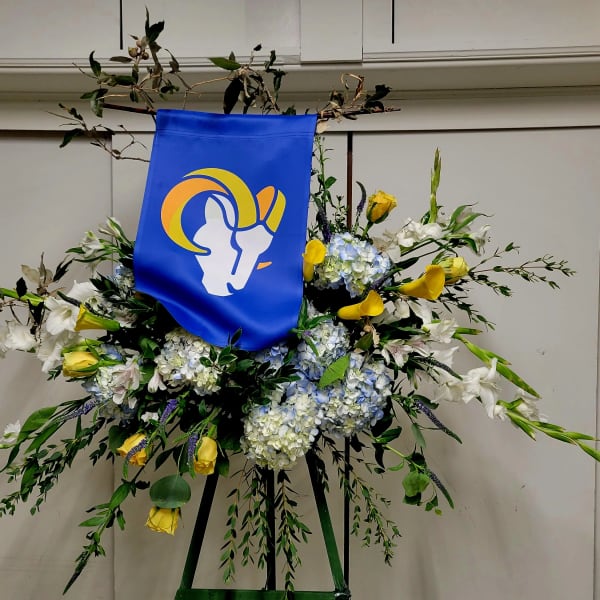 Large floral standing spray with blue banner and yellow-white flowers