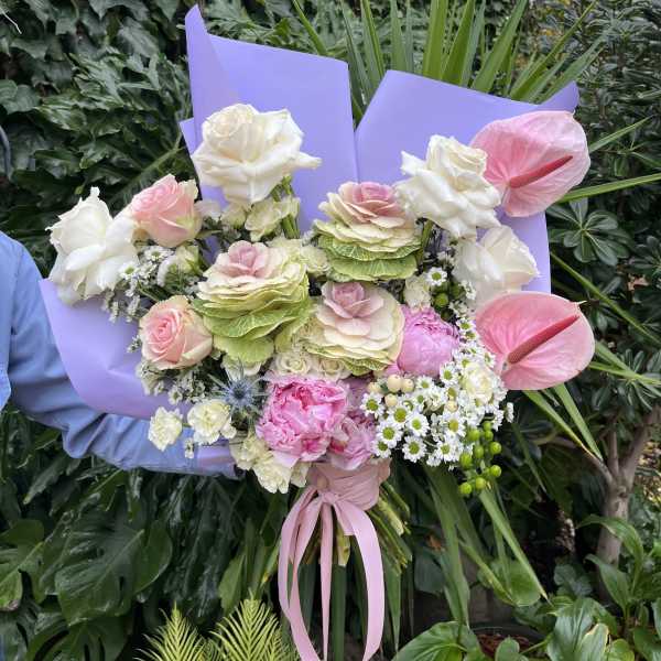 Bouquet of pink and white flowers wrapped in lavender paper