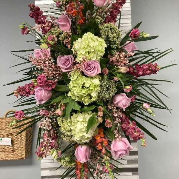 Tall arrangement of pink roses and green hydrangeas with mixed blooms