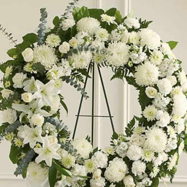 Large white floral wreath on a black stand