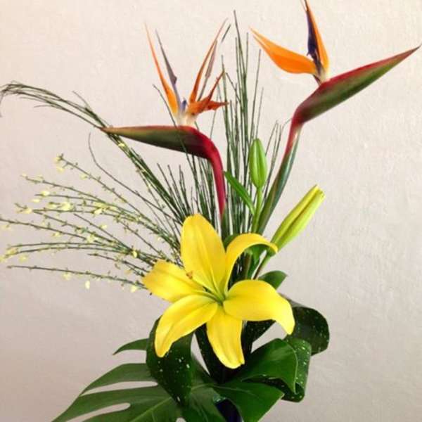 Tropical arrangement with yellow lily and bird-of-paradise flowers