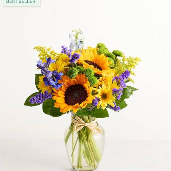 Sunflower bouquet in a clear glass vase with purple and yellow accents