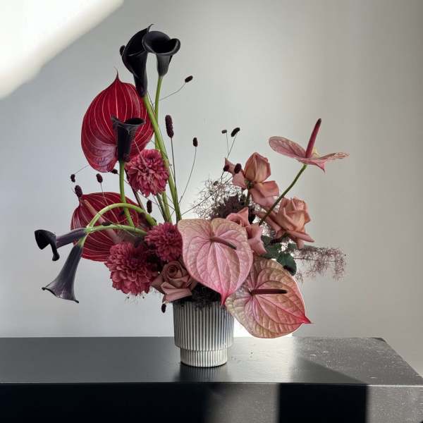 Pink and black floral arrangement in a ribbed vase