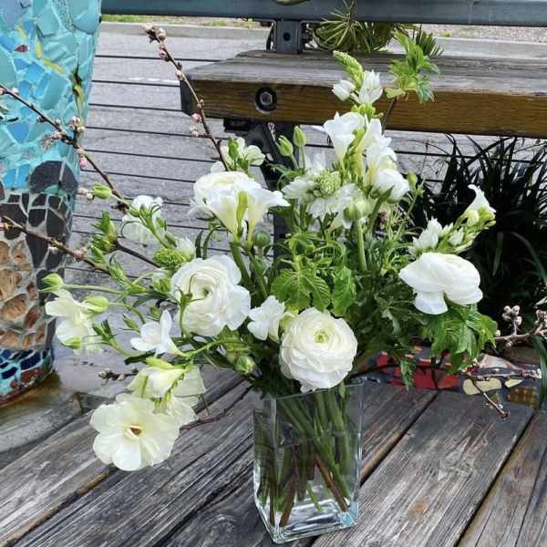 White floral arrangement in a clear glass vase on a wooden table