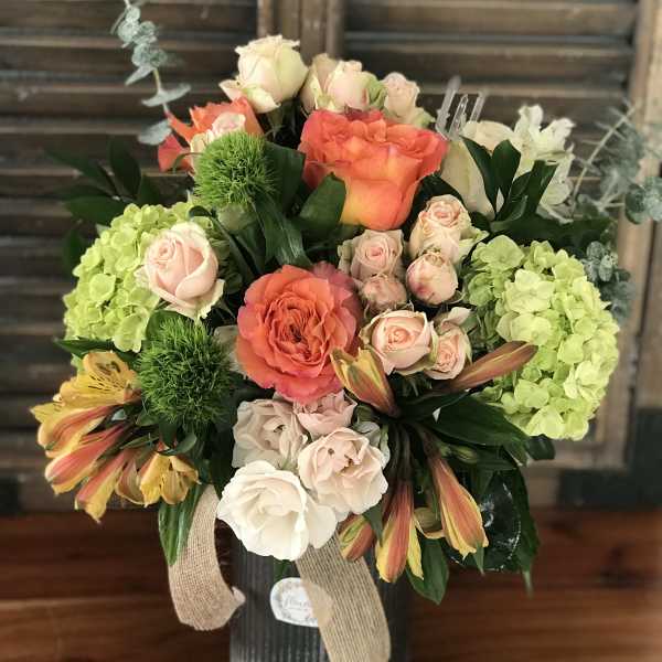 Mixed bouquet in a ribbed vase with coral and blush roses