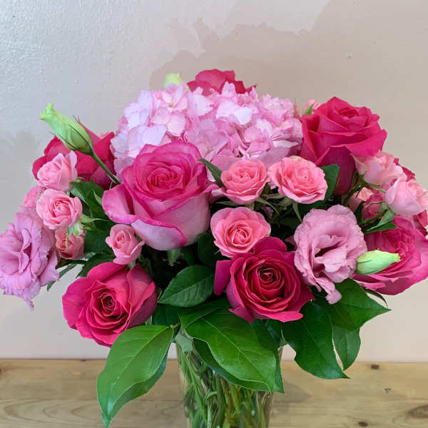Pink roses and lisianthus arranged in a clear glass vase