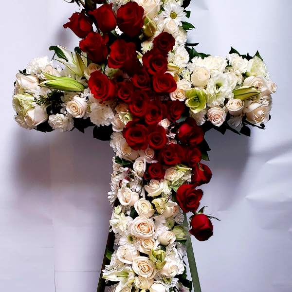 Cross-shaped floral arrangement with red and white roses on a stand