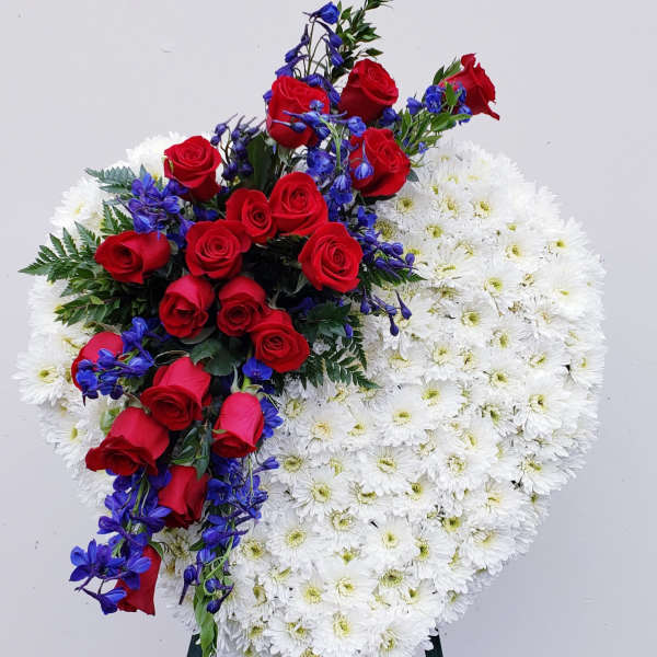 Heart-shaped floral spray with red roses, white daisies, and blue flowers