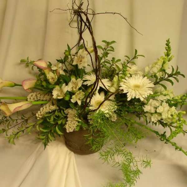 White floral arrangement with calla lilies and daisies in a brown vase