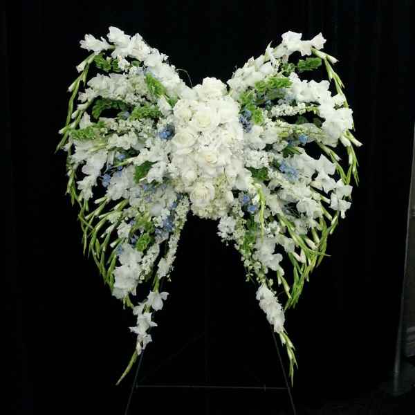 Large white floral spray arranged in a winged shape on a stand