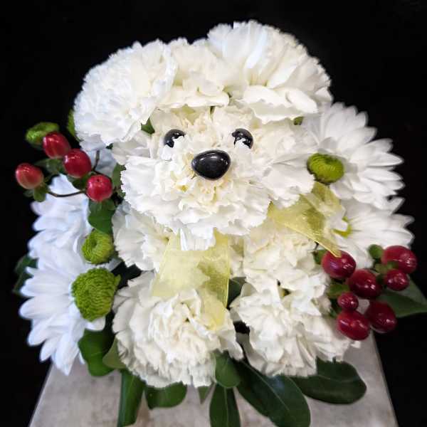 White flower arrangement shaped like a teddy bear with red berry accents