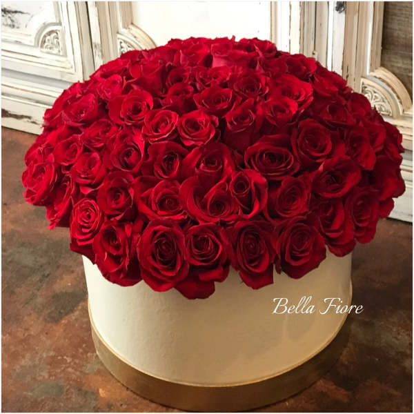 Large round arrangement of red roses in a white hat box
