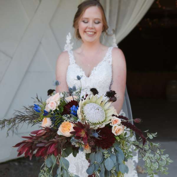 Bride holding a large cascading bouquet with mixed flowers and greenery
