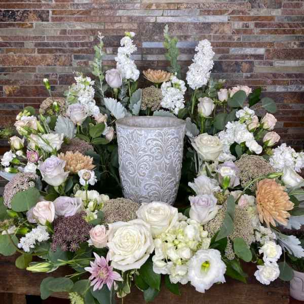 Symmetrical floral arrangement around a decorative urn with white and blush blooms