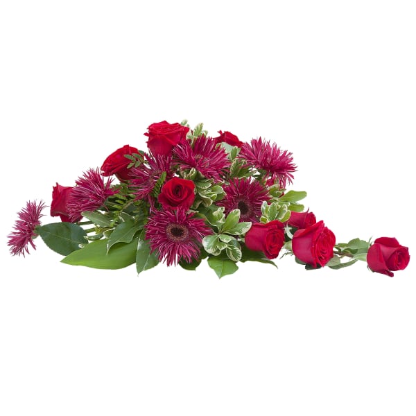 Low spray arrangement of red roses and dark pink mums on a white background