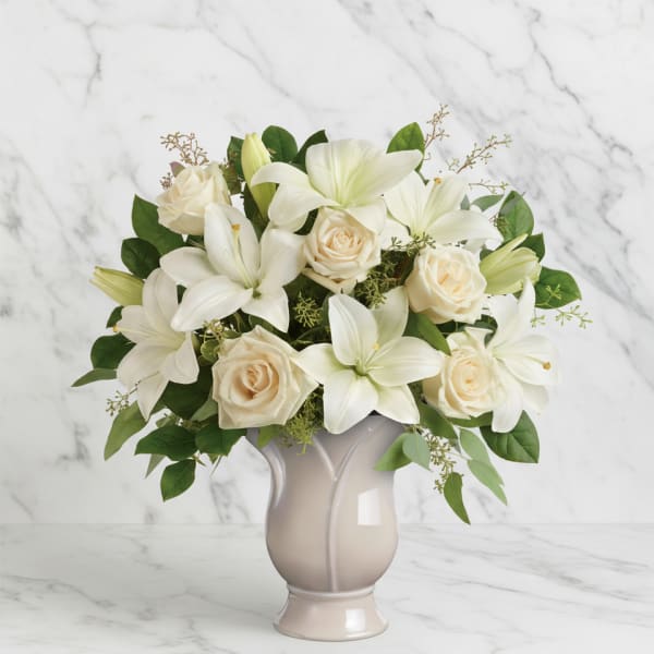 White lilies and cream roses arranged in a beige vase