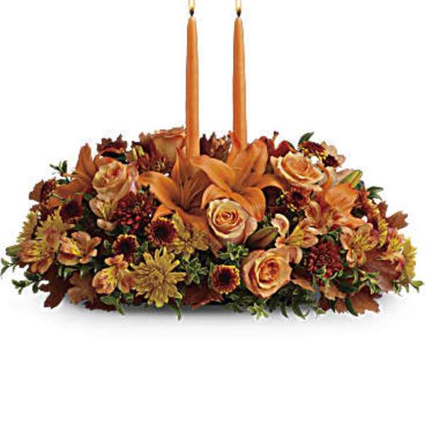 Orange floral centerpiece with two lit taper candles