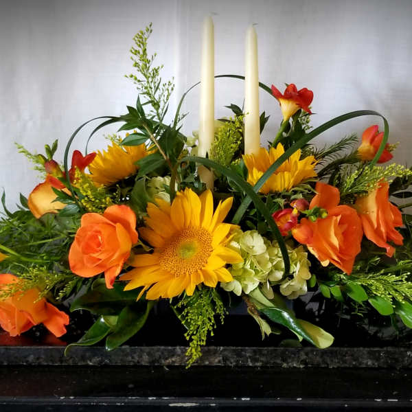 Orange and yellow floral centerpiece with tall white candles