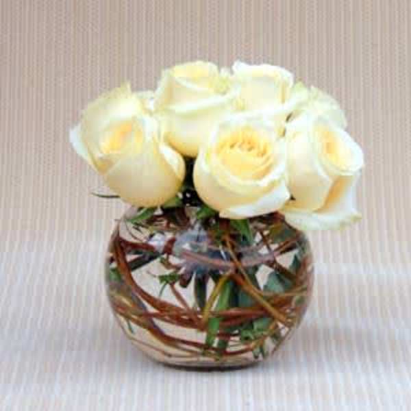 Cream roses arranged in a round glass vase