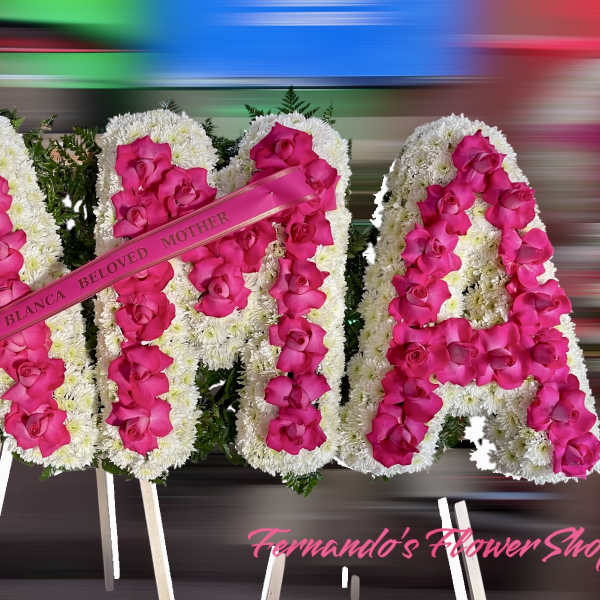 Standing floral letters with white blooms and hot pink roses spelling AMA with memorial ribbon