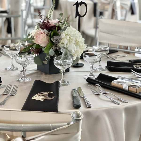 Round table centerpiece with pale pink and white flowers in a black vase