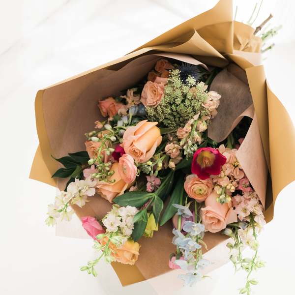 Wrapped bouquet of peach and pink flowers with mixed blooms