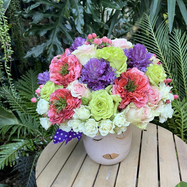 Colorful bouquet of roses and purple flowers in a white vase